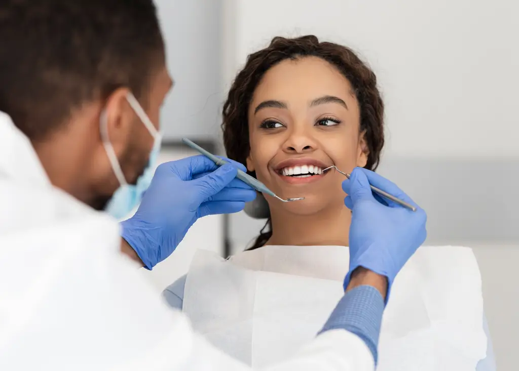 Pretty black lady in dentist chair looking at her doctor with smile, close up