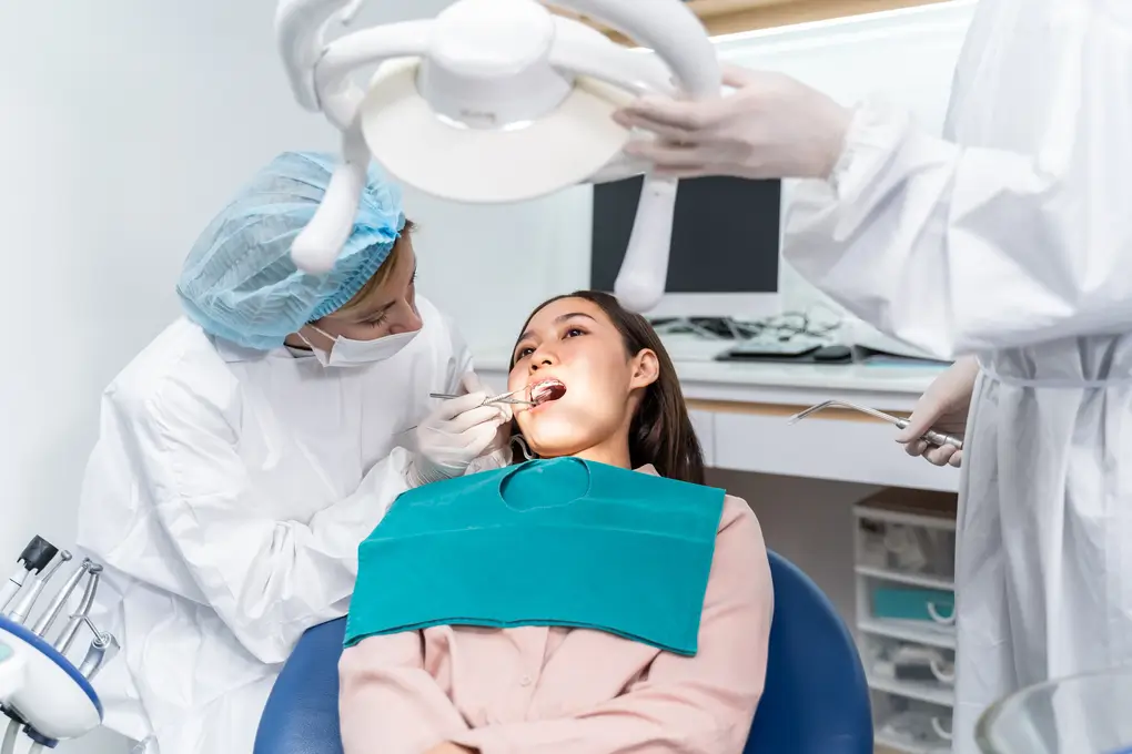 Orthodontist doctor examine tooth to woman patient at dental clinic. Attractive young girl with braces lying on dental chair, getting dental treatment from dentist during procedure service in hospital